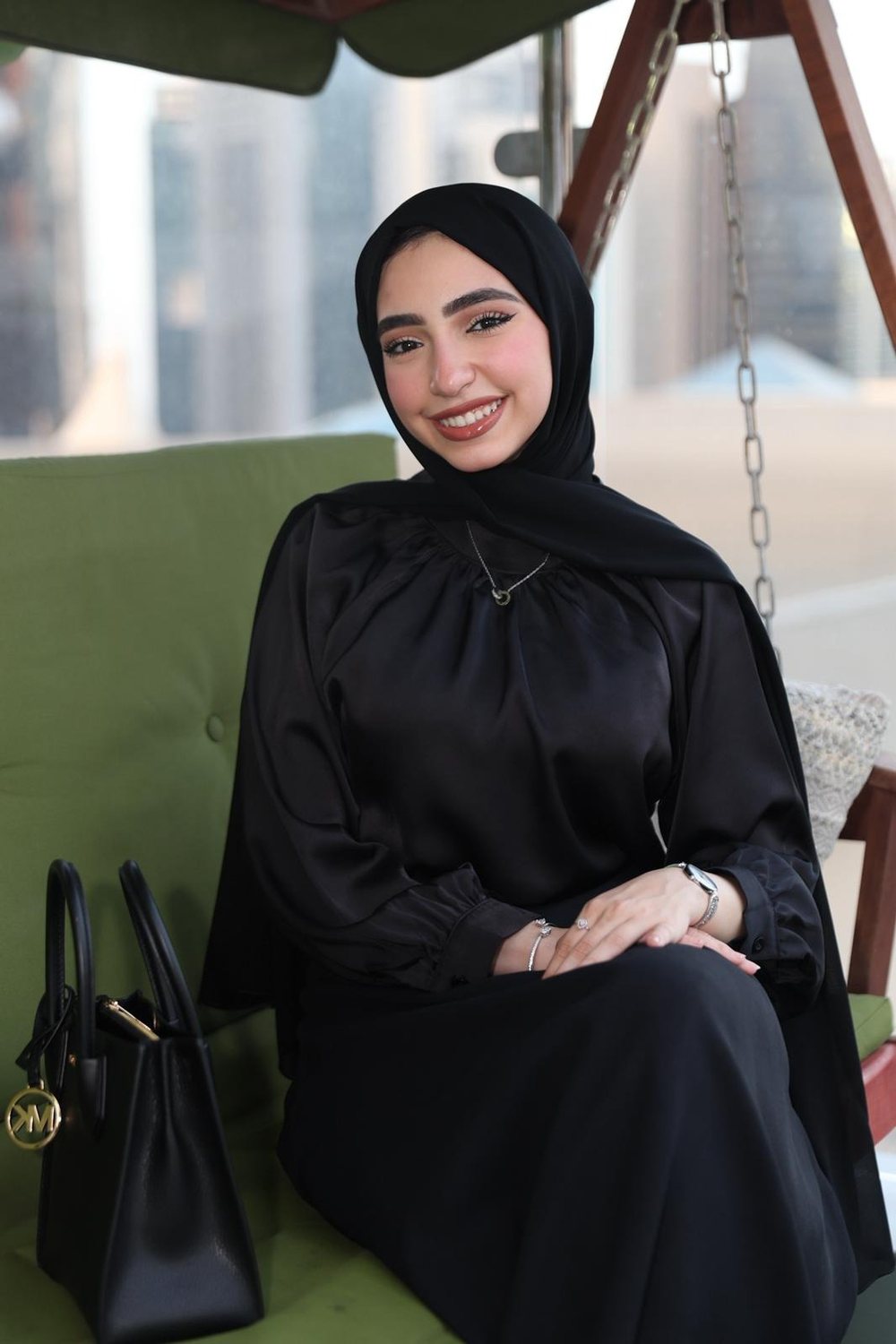 Sara AbuSadeh seated on a green garden swing
